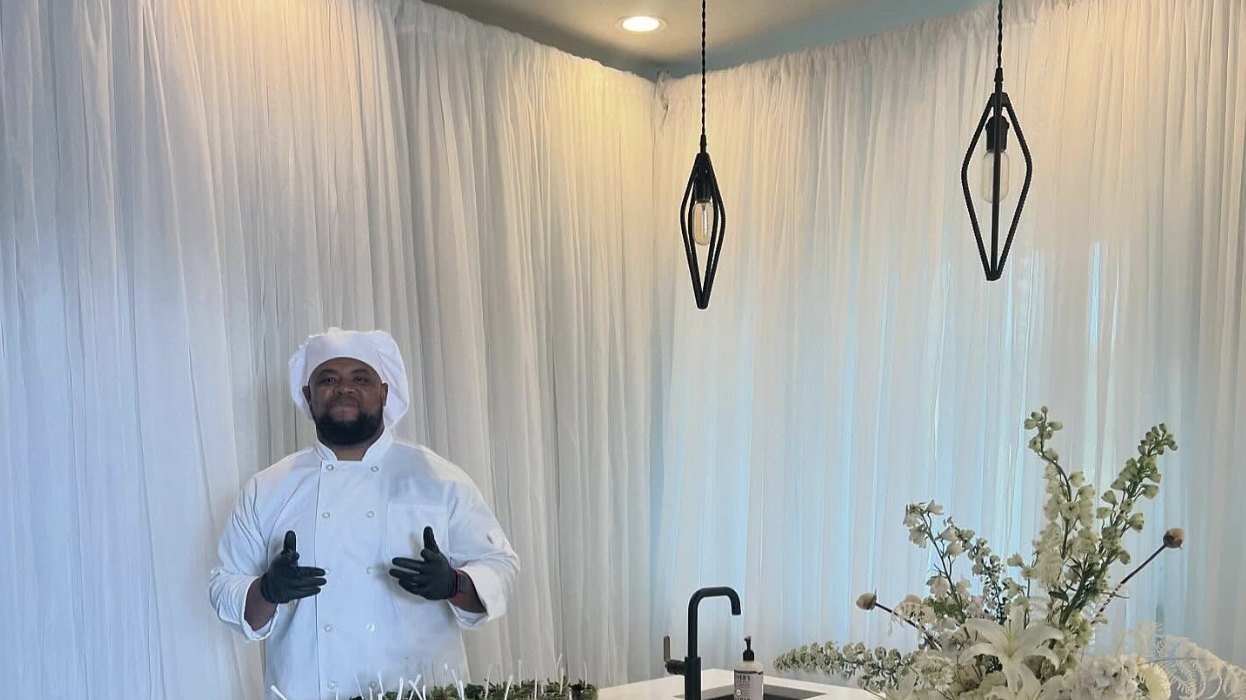 Chef Brandon in a white coat behind an elegant tasting table of small bites